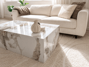 Sofabord i marmor imitasjon i stue med lys beige sofa og dekorativ vase.
