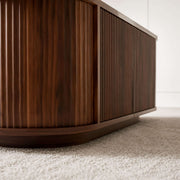 Ovalt Salongbord with a rich walnut finish, showcasing modern design and elegant ribbed texture.